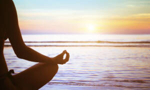 Yogi on the beach practicing mindfulness at sunrise