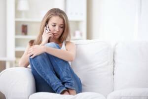 Girl sitting on couch on the phone for her teletherapy session